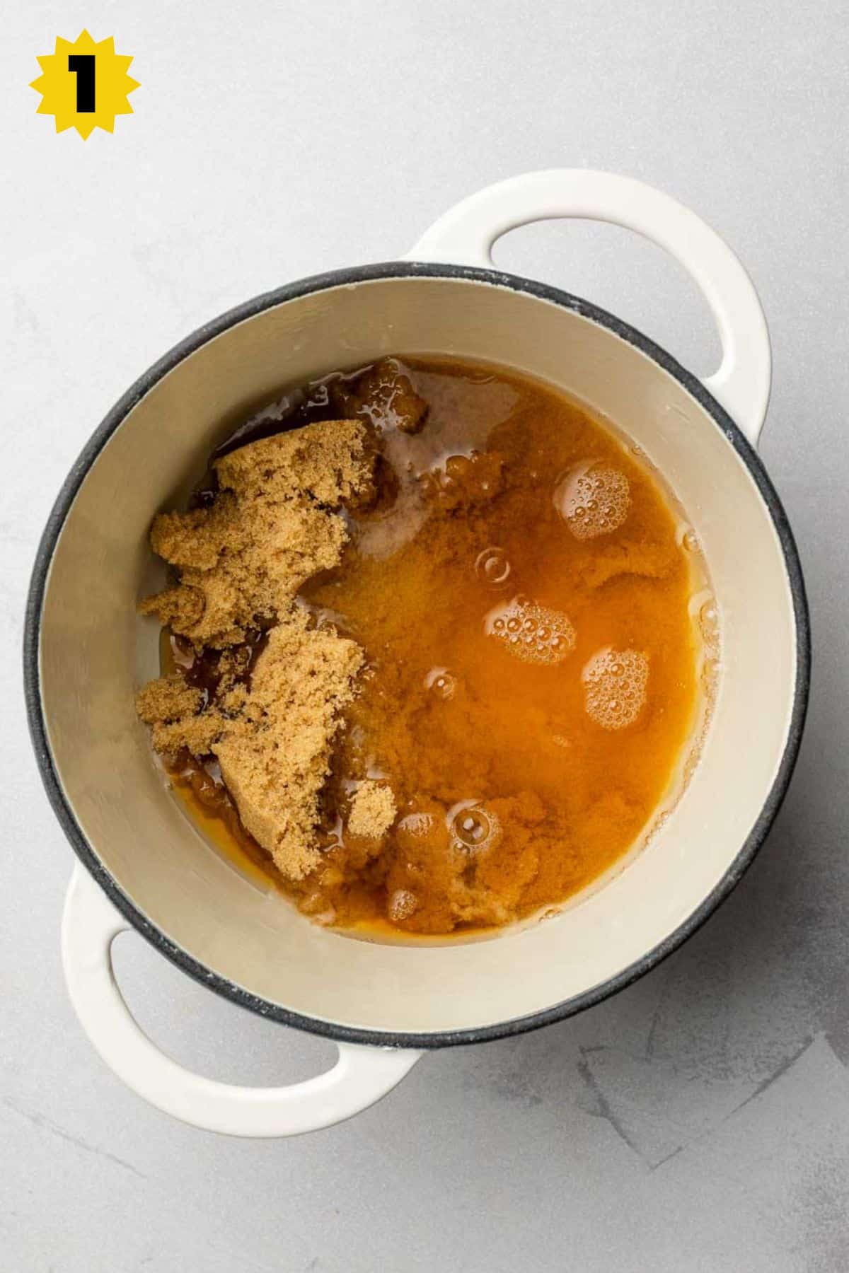 Water and brown sugar in a small white enameled cast iron pot.
