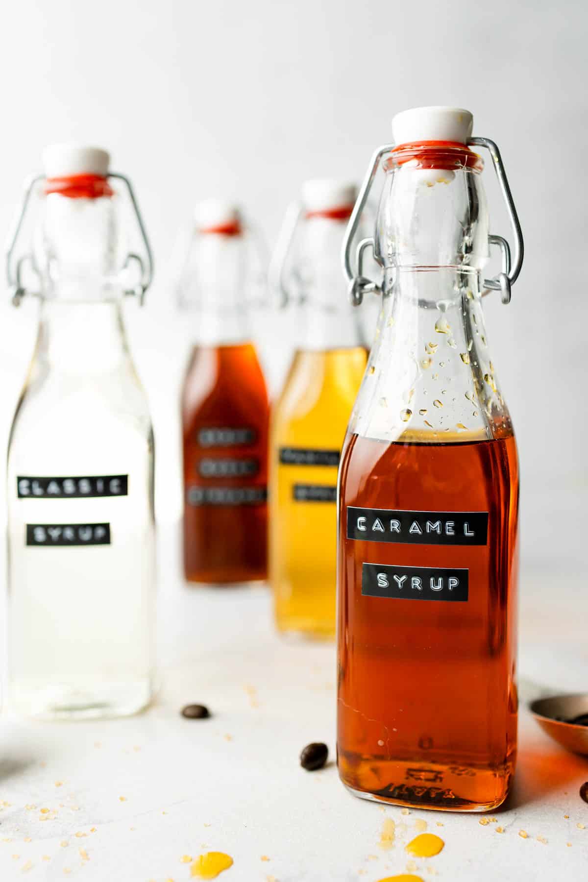 Caramel syrup in glass bottle with swing top lid next to other homemade coffee syrups.