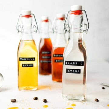 A glass bottle with classic syrup next to some other syrups in bottles.