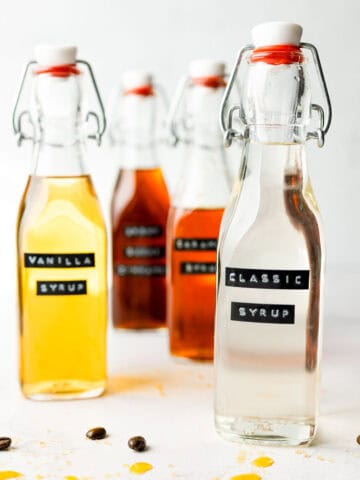 A glass bottle with classic syrup next to some other syrups in bottles.
