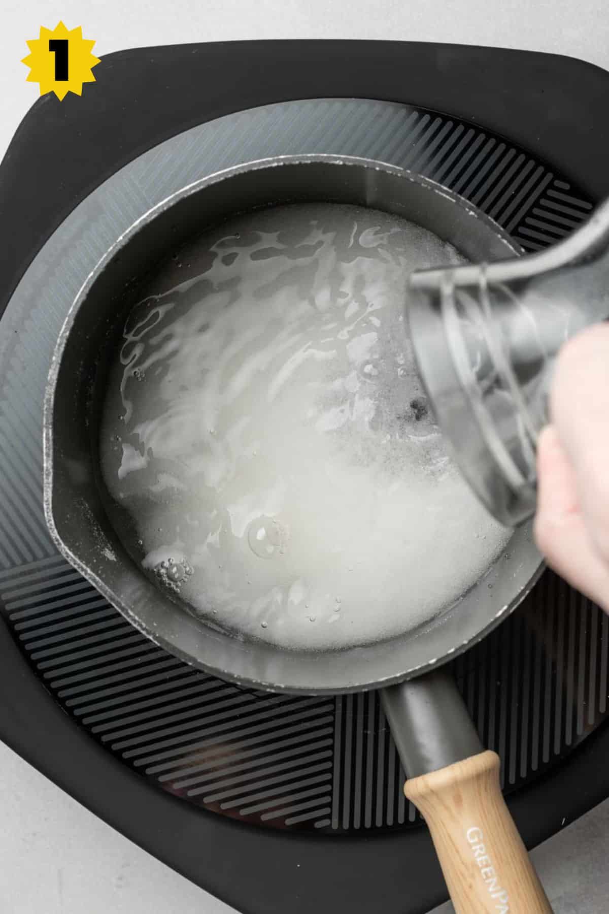 Pouring water into small saucepan with granulated sugar.