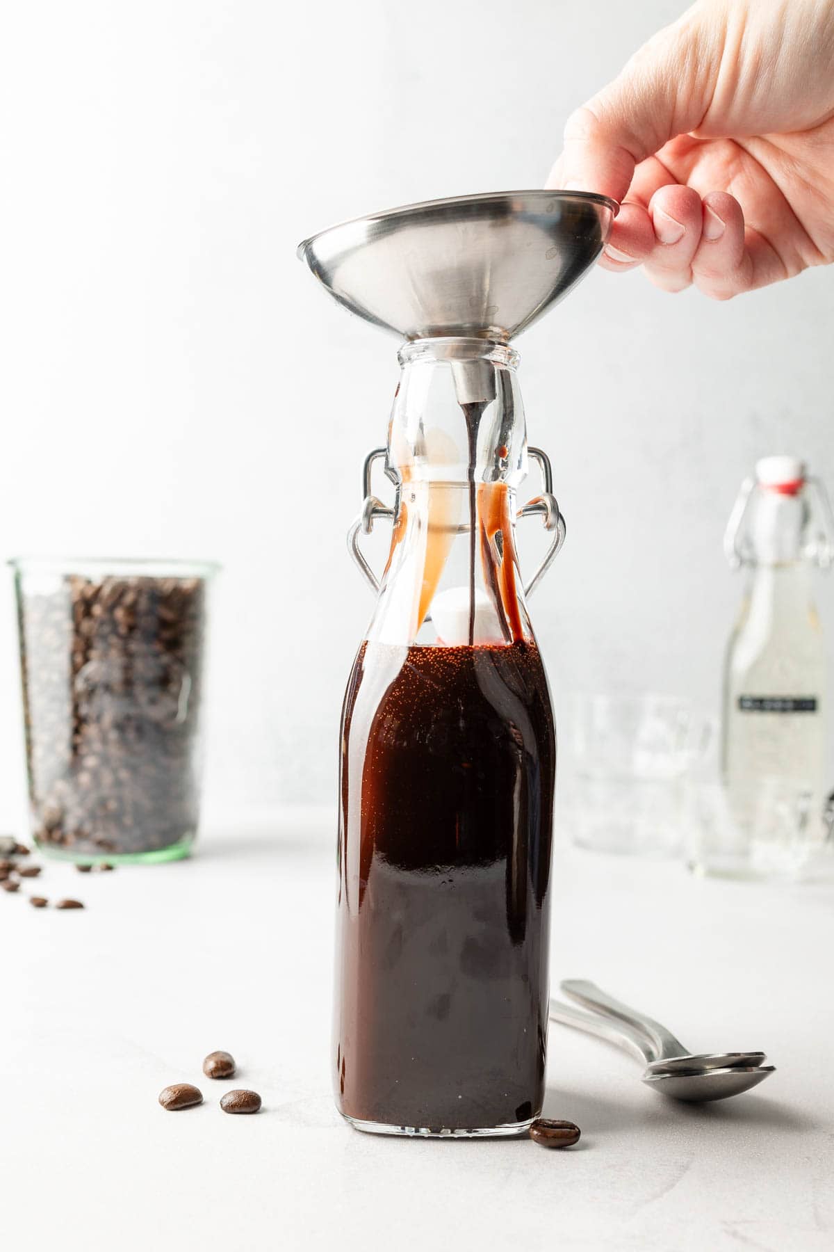 Mocha sauce poured into glass jar through funnel.