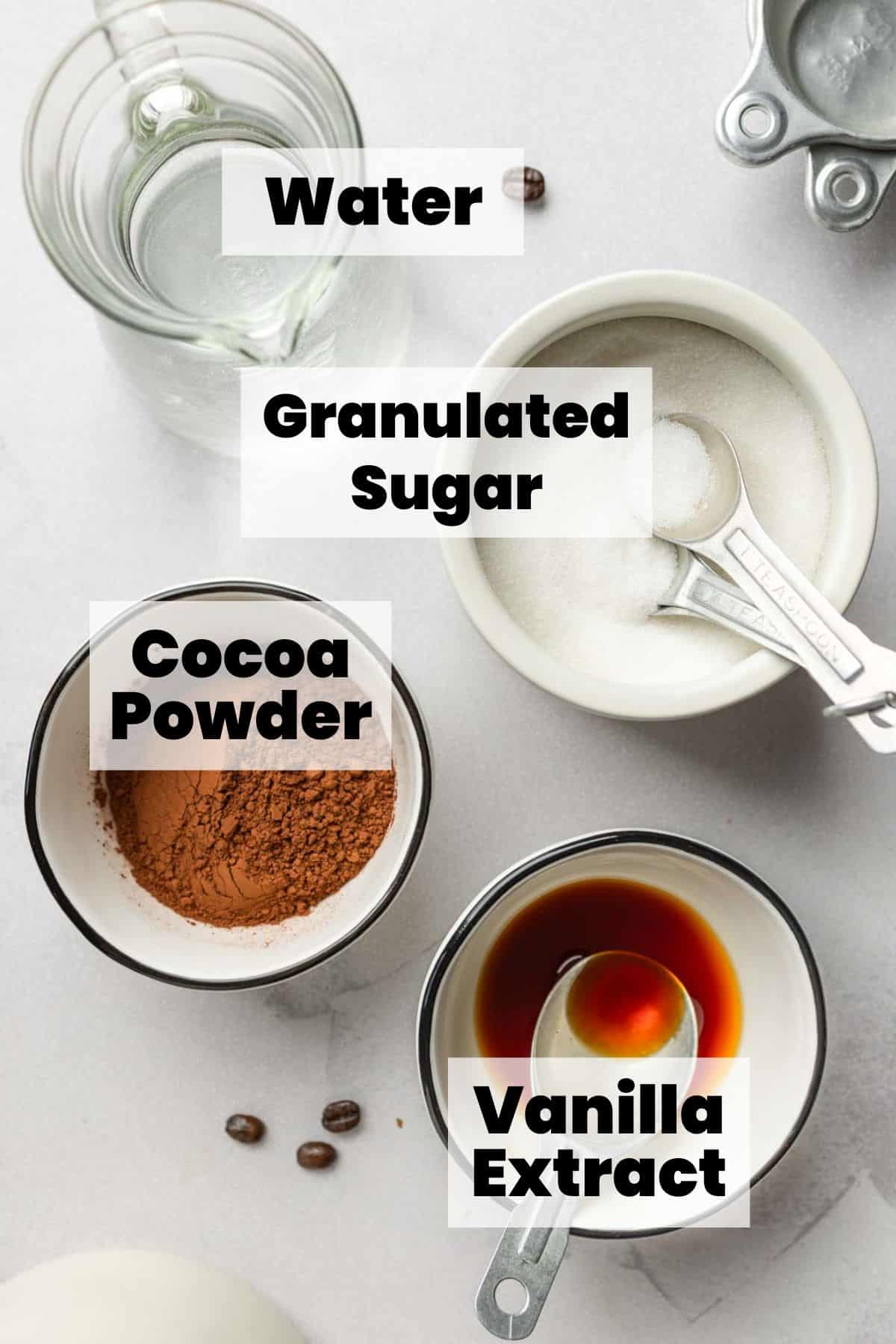 Sugar, cocoa powder, water, and vanilla extract measured out in bowls.