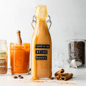 Pumpkin spice sauce drizzling down the side of a tall glass jar.