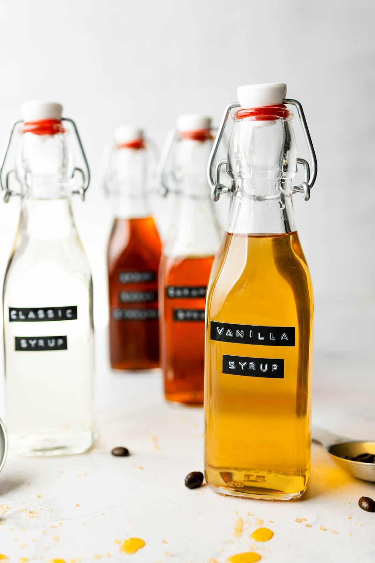 Vanilla syrup in glass swing top bottle in front of other visits.