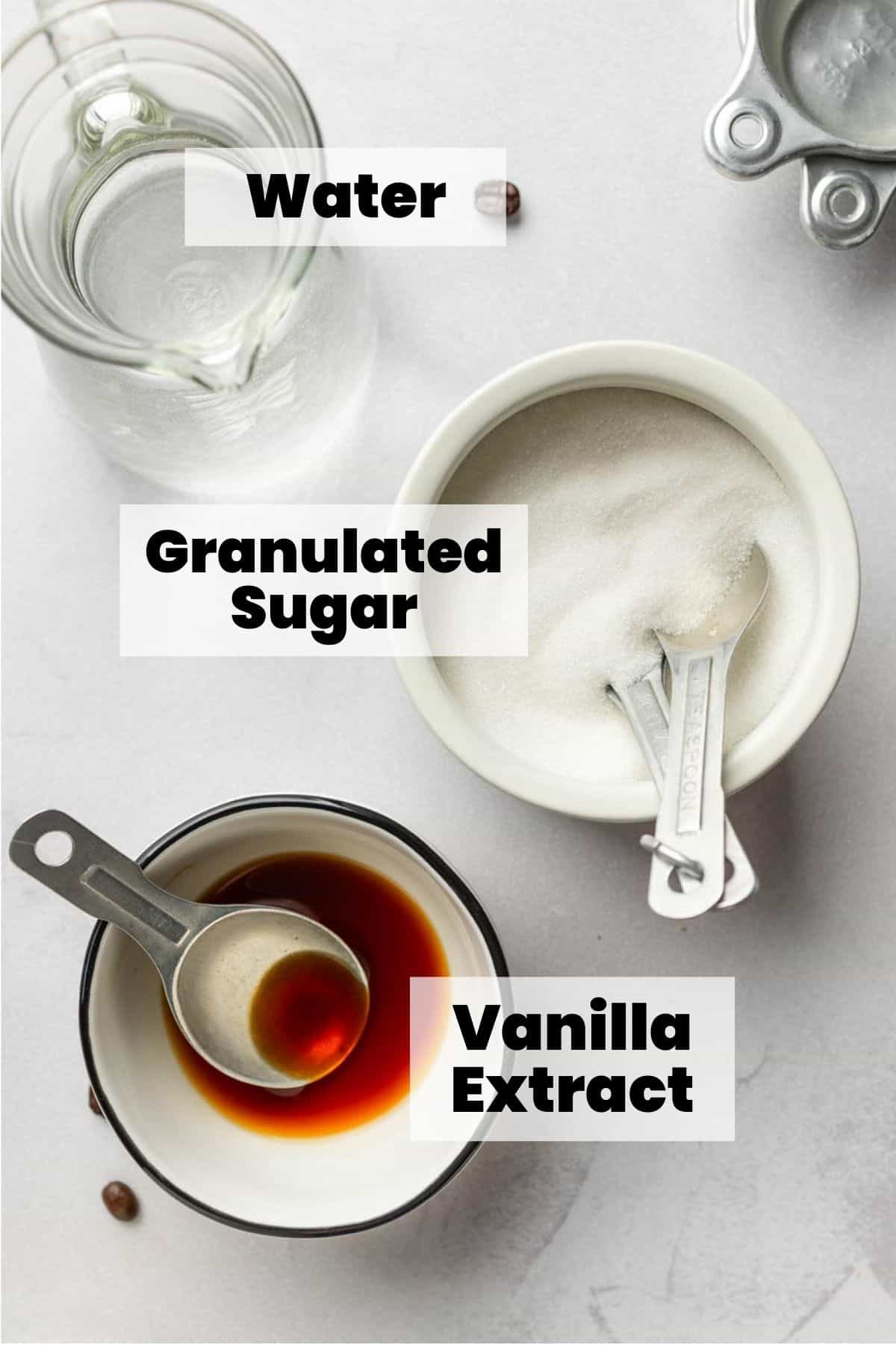 Granulated sugar, vanilla extract, and water measured out in bowls and cups.