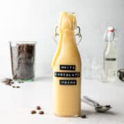 White chocolate mocha sauce in tall glass bottle, with drips down the sides.