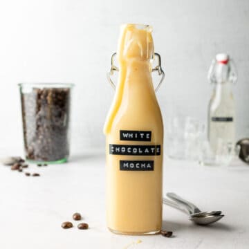 White chocolate mocha sauce in tall glass bottle, with drips down the sides.