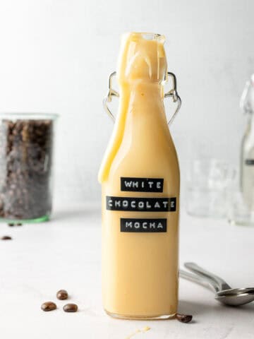 White chocolate mocha sauce in tall glass bottle, with drips down the sides.