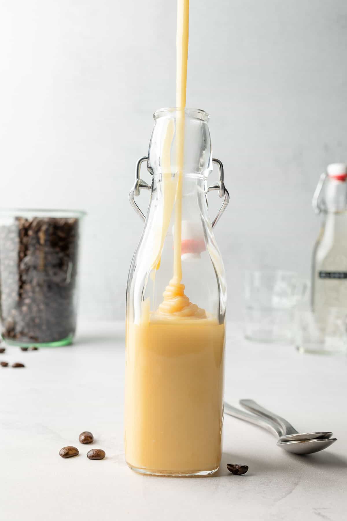 Pouring white chocolate mixture into tall glass jar.