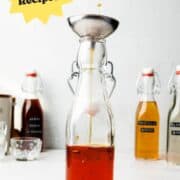 Caramel syrup pouring into glass bottle through metal funnel.