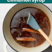 Spatula in pot with brown sugar liquid and cinnamon sticks floating in it