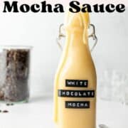 White chocolate mocha sauce in tall glass bottle, dripping down the side.