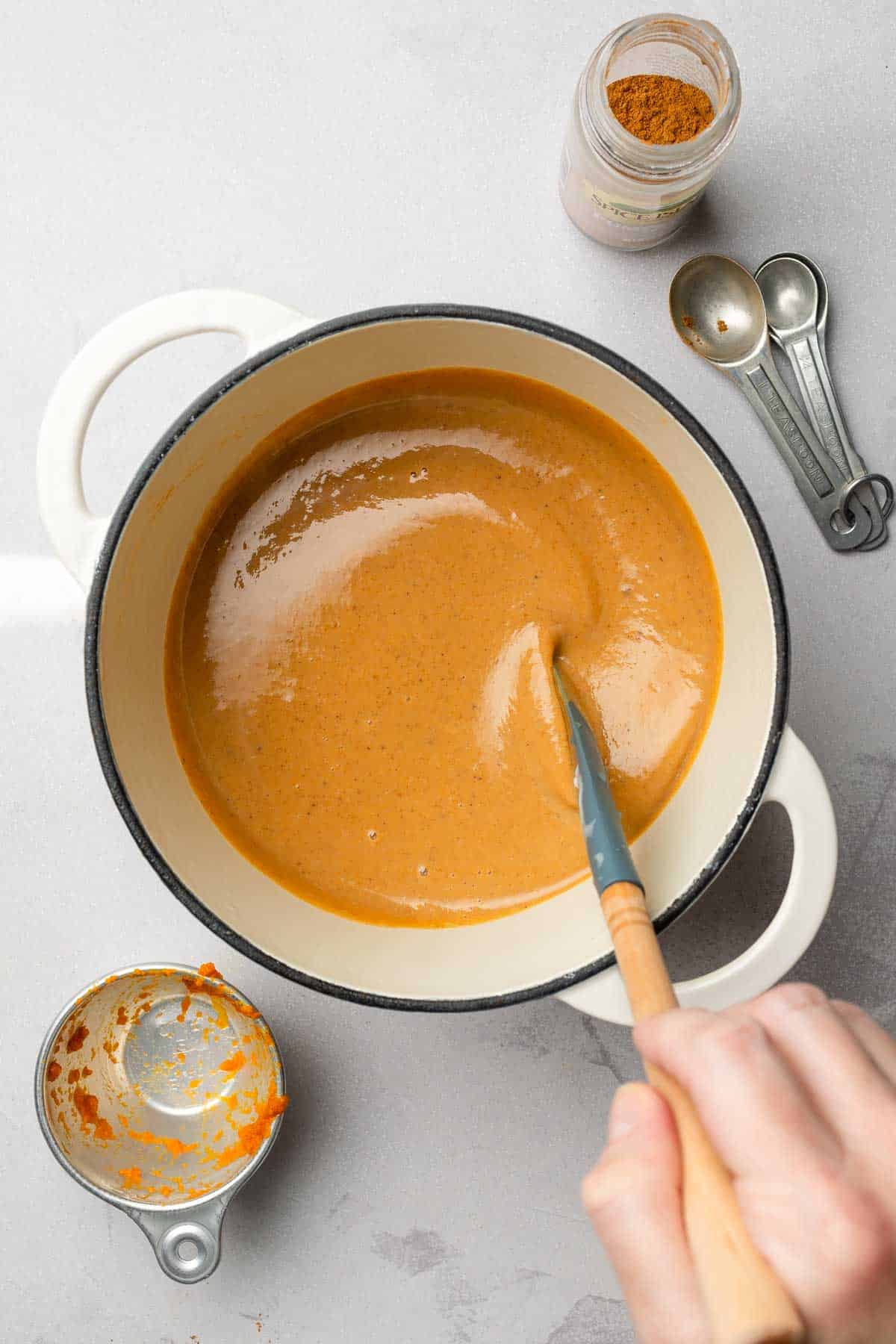 Smooth pumpkin spice sauce in pan stirred by hand.