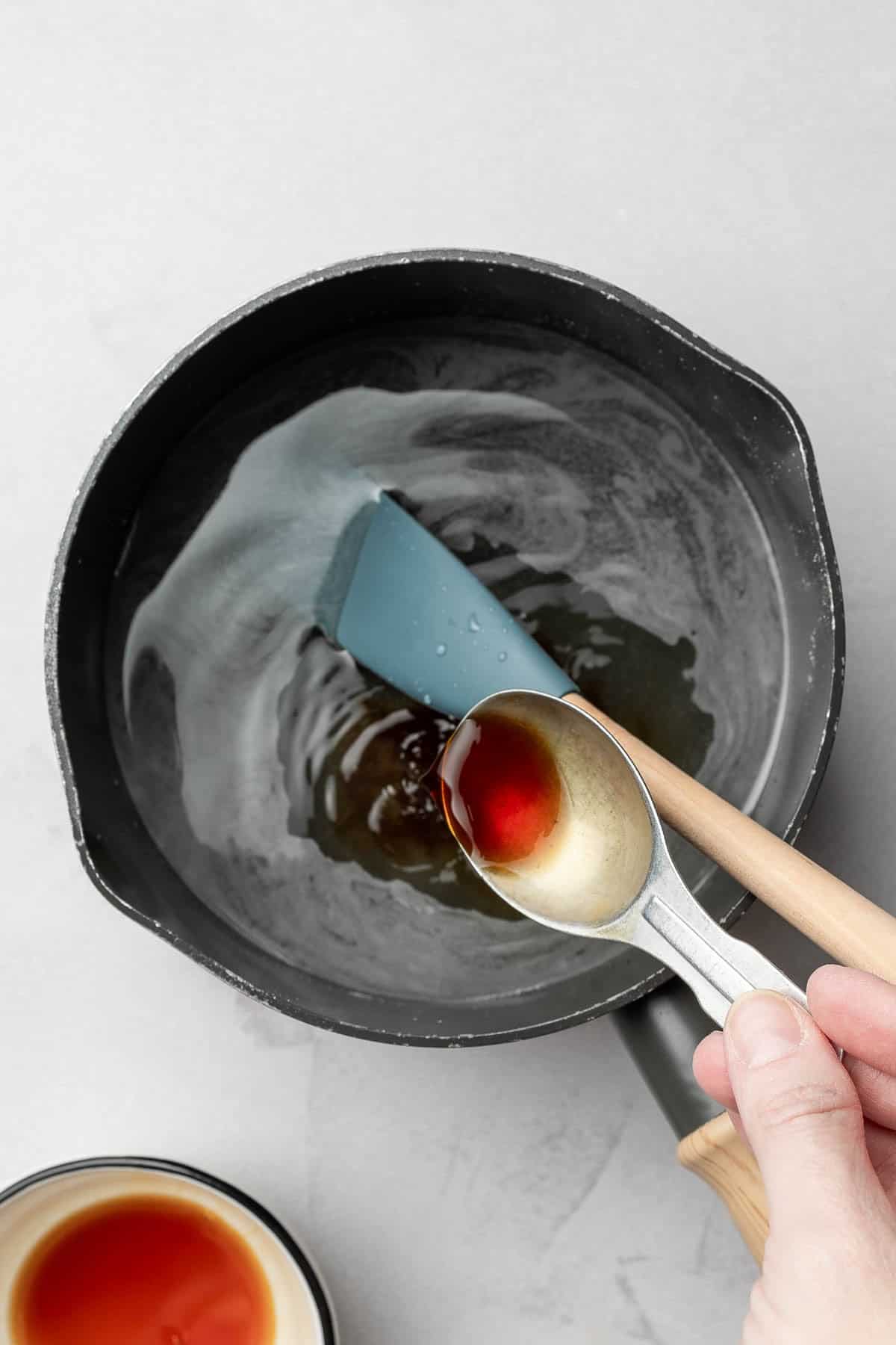 Adding vanilla extract to small sauce pan.
