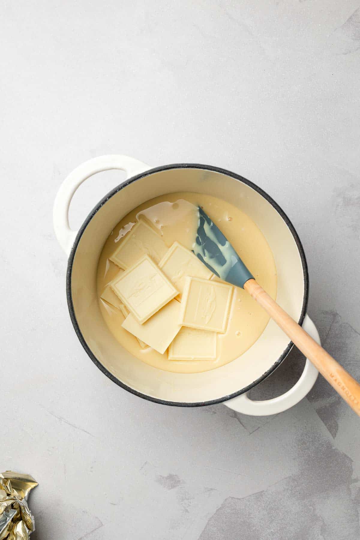 White chocolate squares sit atop sweetened condensed milk in small saucepan.