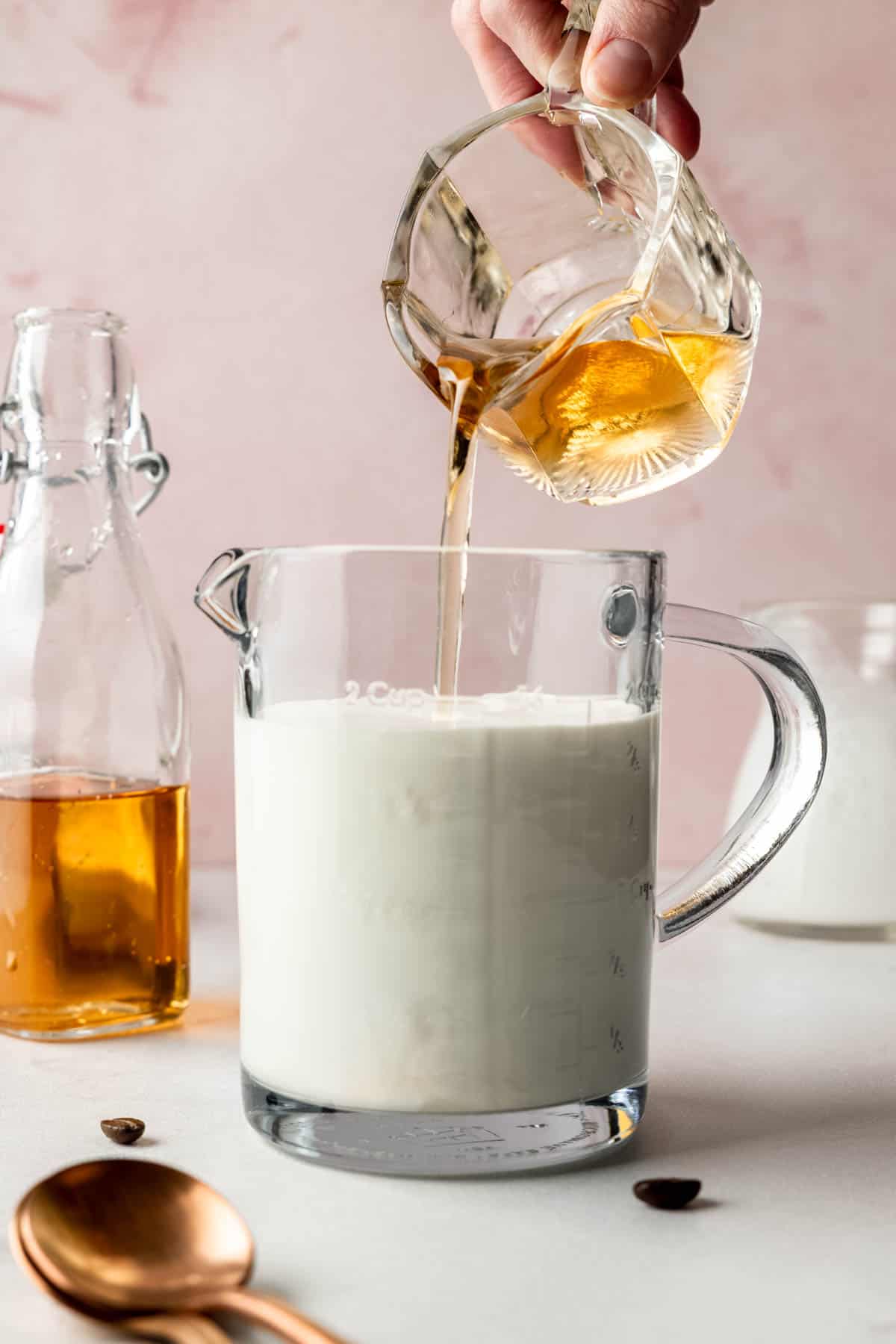 Vanilla syrup being poured into the measuring cup of milk and cream, ready to be mixed for sweet cream.