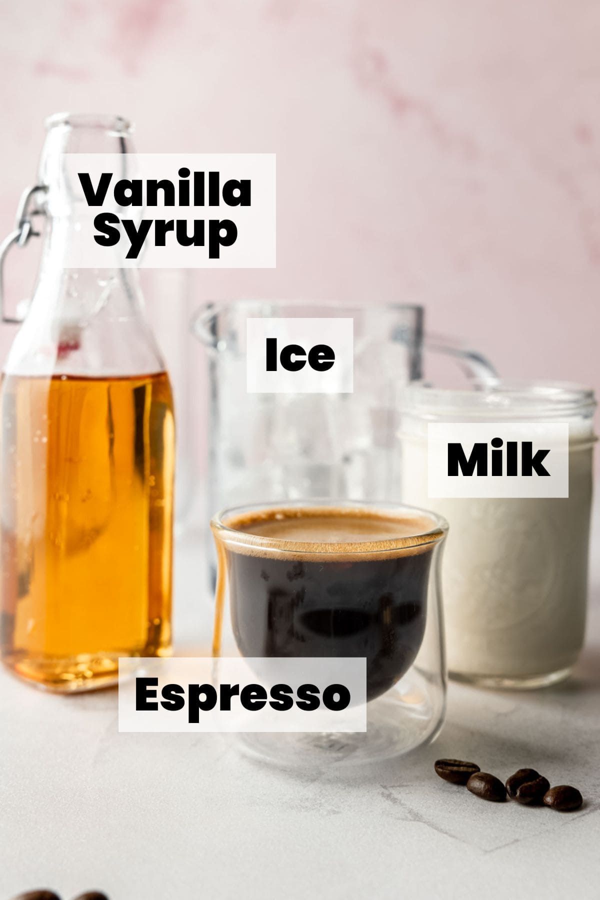 ngredients labeled: vanilla syrup, ice, milk, and espresso shown side by side on a countertop with coffee beans scattered nearby.