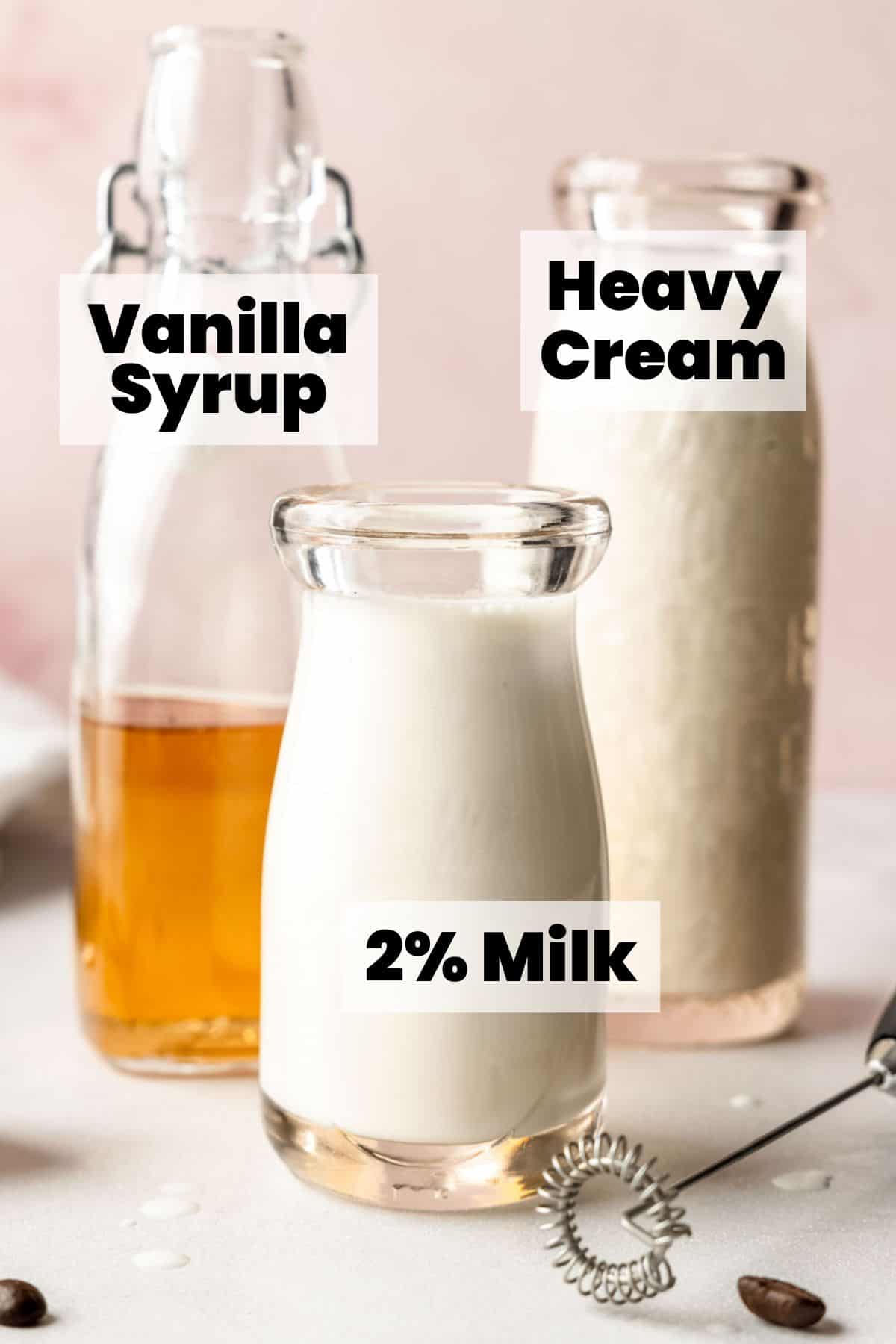 Bottles of vanilla syrup, 2% milk, and heavy cream labeled as ingredients for making vanilla sweet cream cold foam.