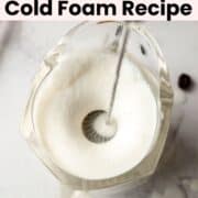 Vanilla sweet cream fully frothed into cold foam using a handheld milk frother in a glass measuring cup.