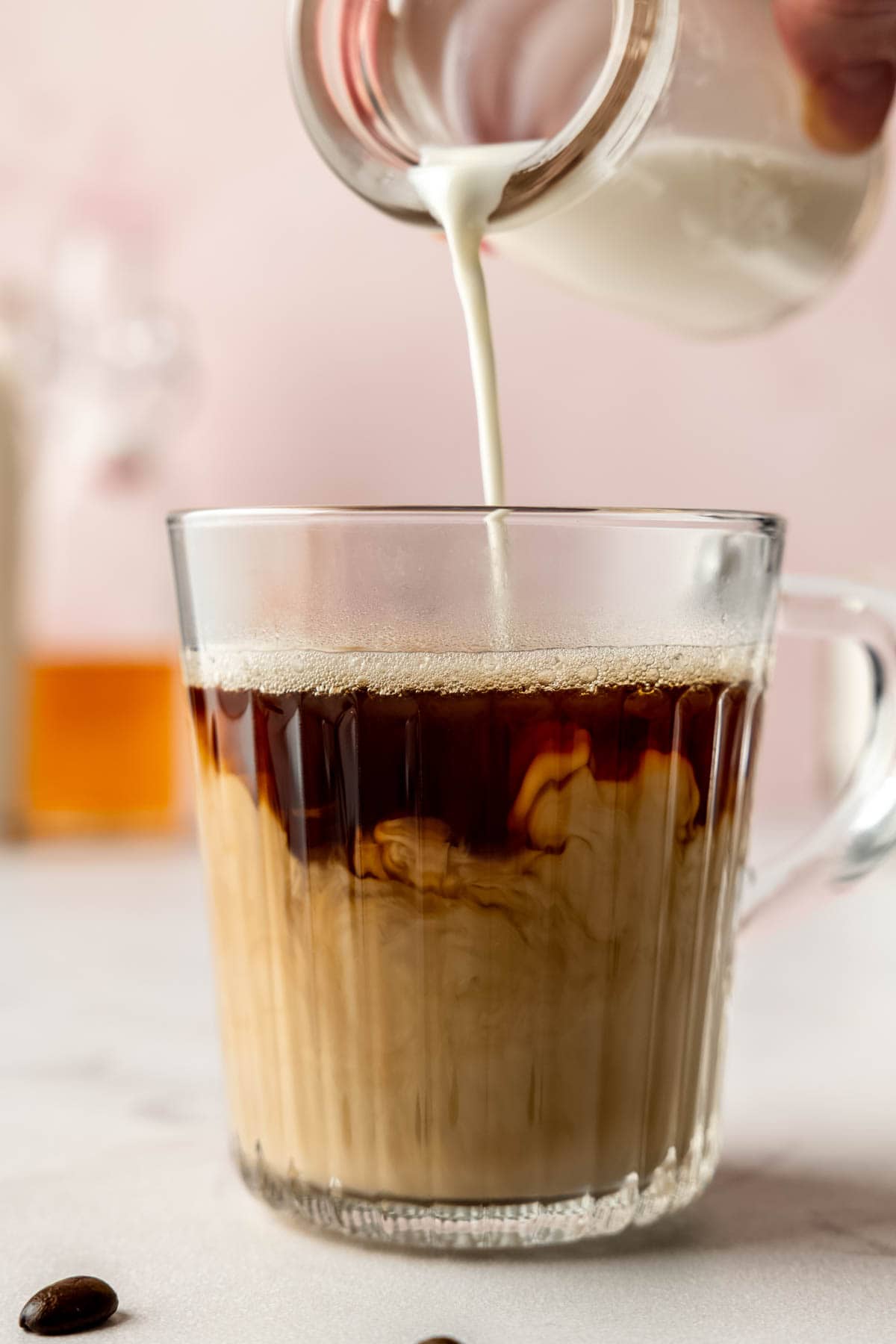 Homemade vanilla sweet cream being poured into a cup of coffee, creating creamy swirls.