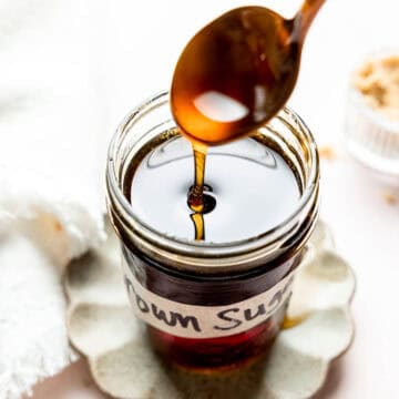 Brown sugar syrup pouring from spoon into a mason jar.
