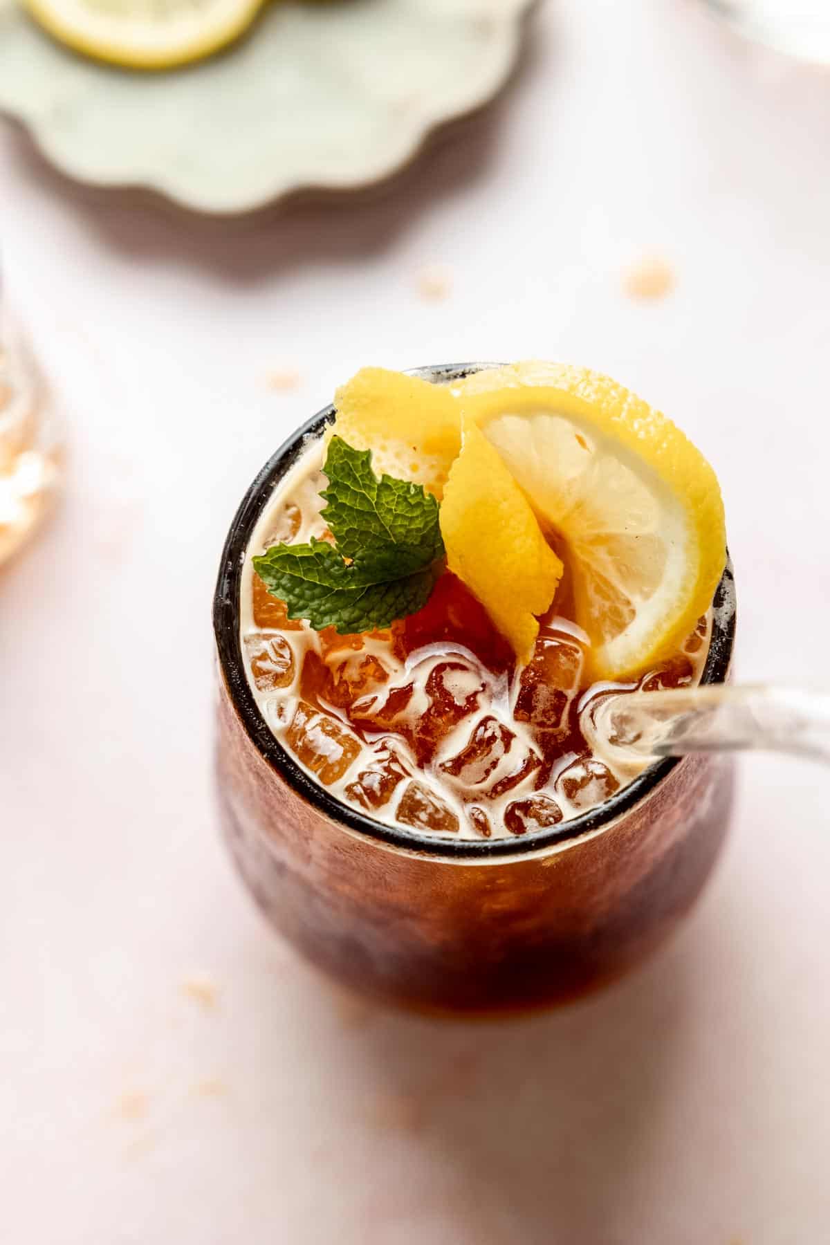 A glass of sparkling americano garnished with lemon and mint.
