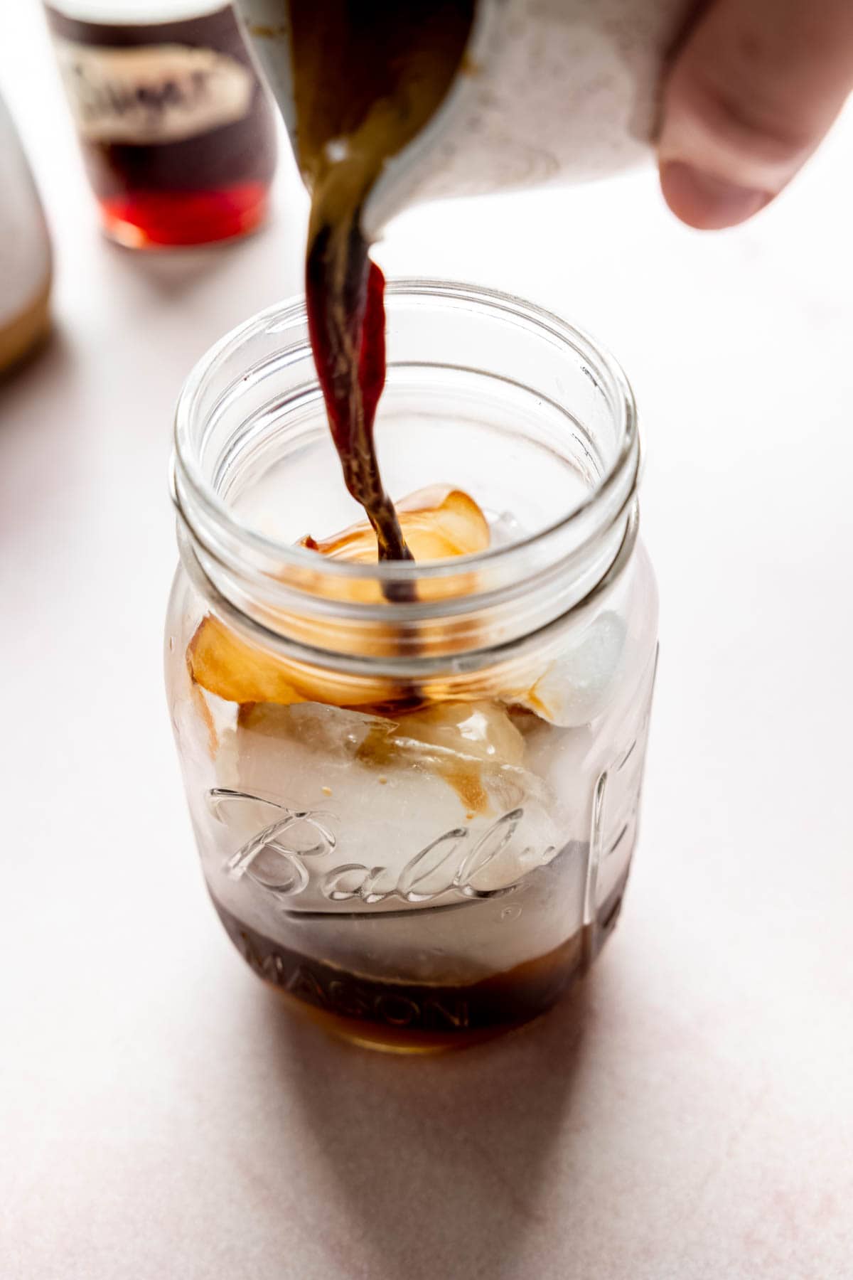 Pouring freshly brewed espresso over ice in a mason jar.