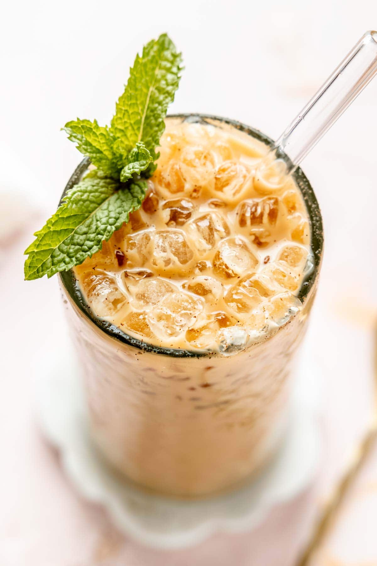 Iced coffee in a tall glass with mint leaves and a spoon.