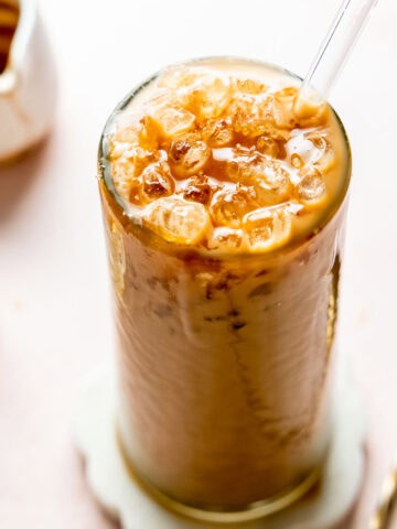 Iced caramel latte in a tall glass topped with caramel drizzle.