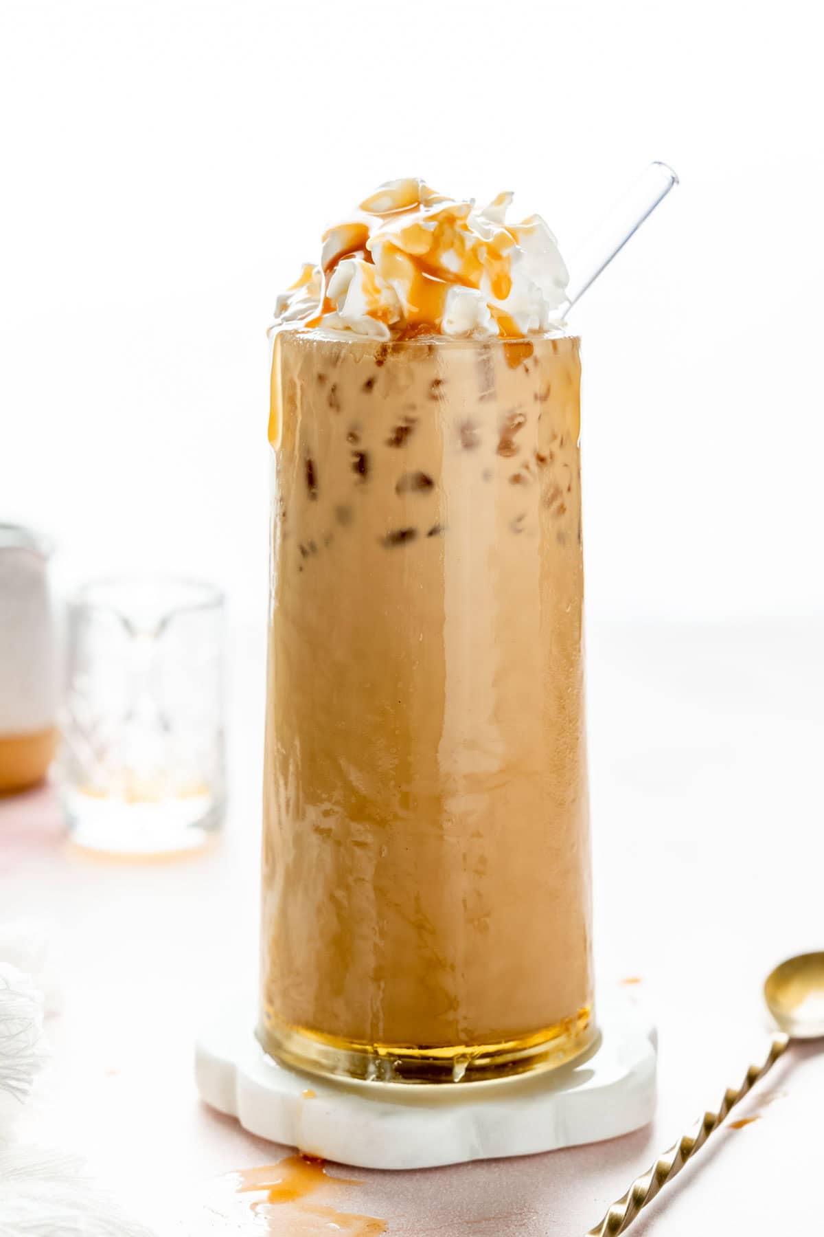 Iced caramel latte in tall glass garnished with whipped cream and caramel drizzle.