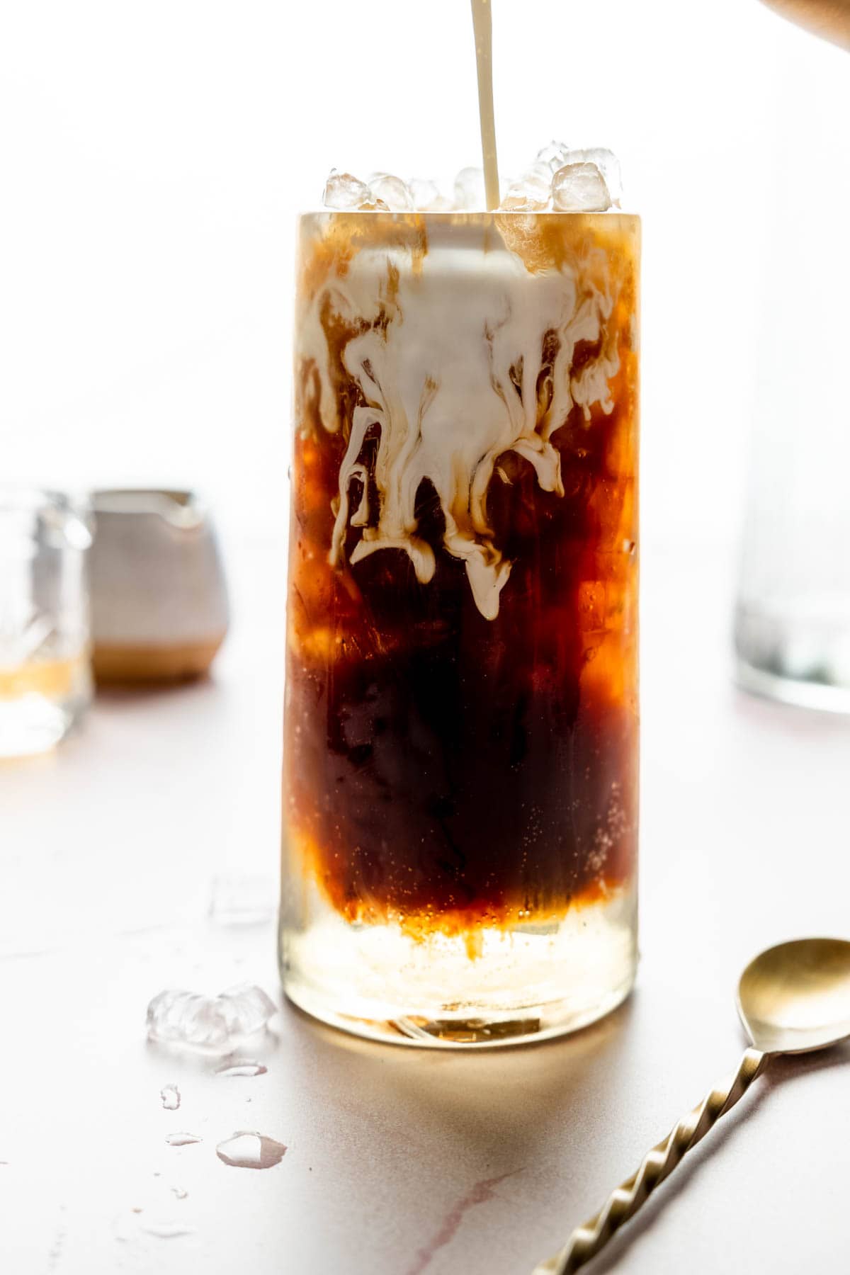 A splash of cream cascading through a dark colored drink.