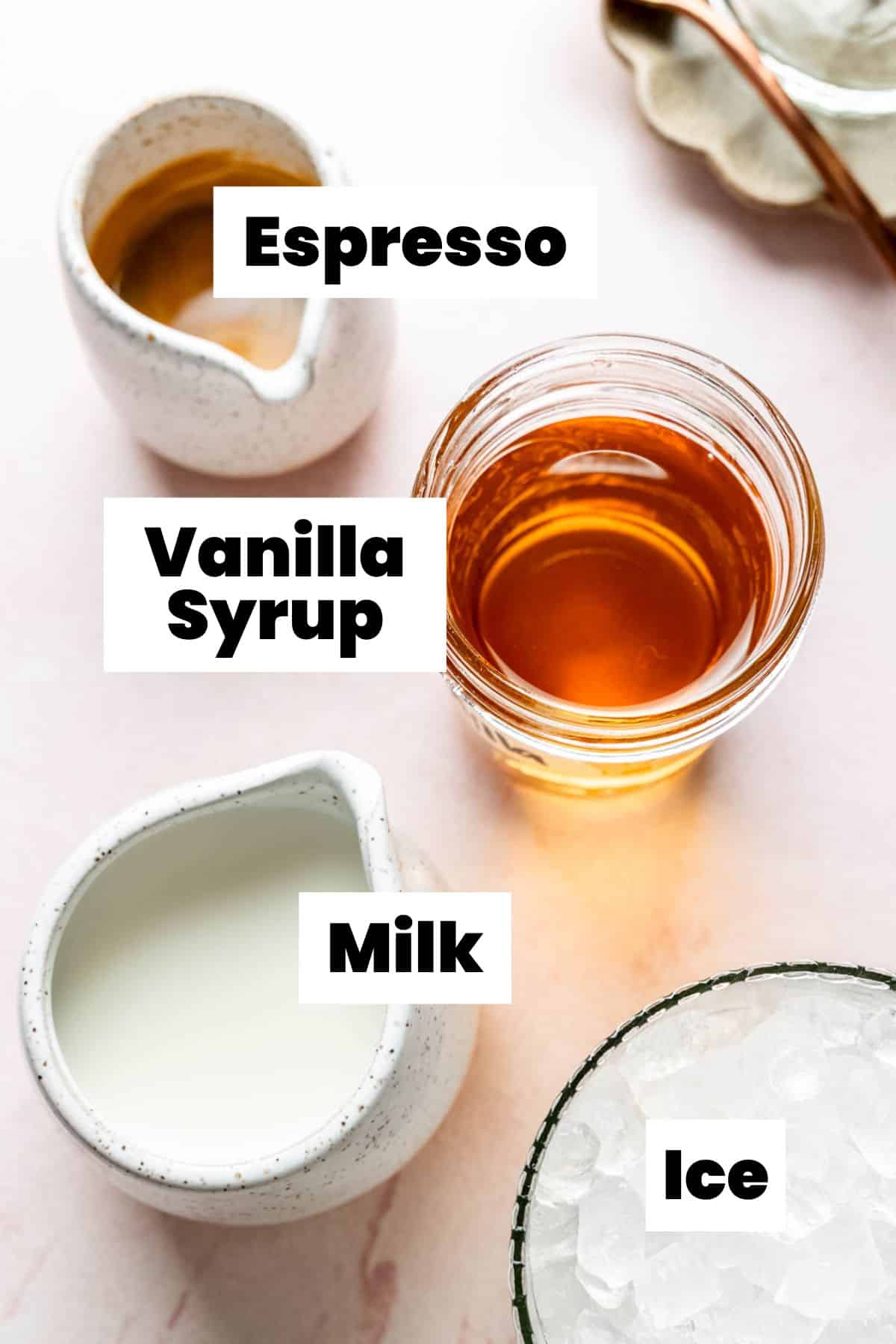 Vanilla syrup, milk, and ice measured out and displayed on pink surface.