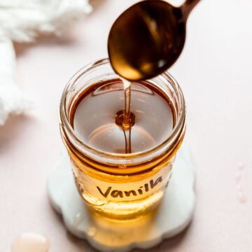 Vanilla syrup pouring from spoon into a mason jar.
