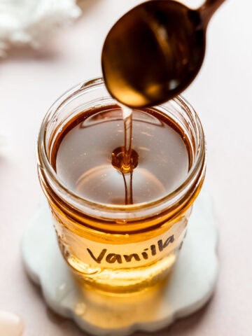 Vanilla syrup pouring from spoon into a mason jar.