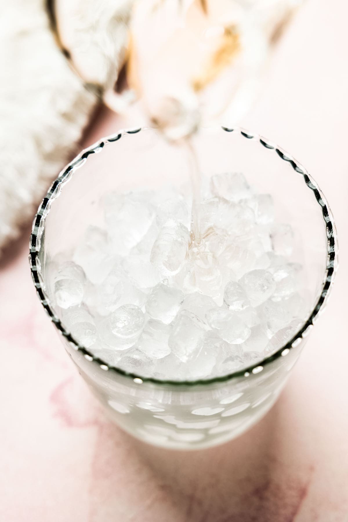 Pouring lavender syrup into glass of ice.