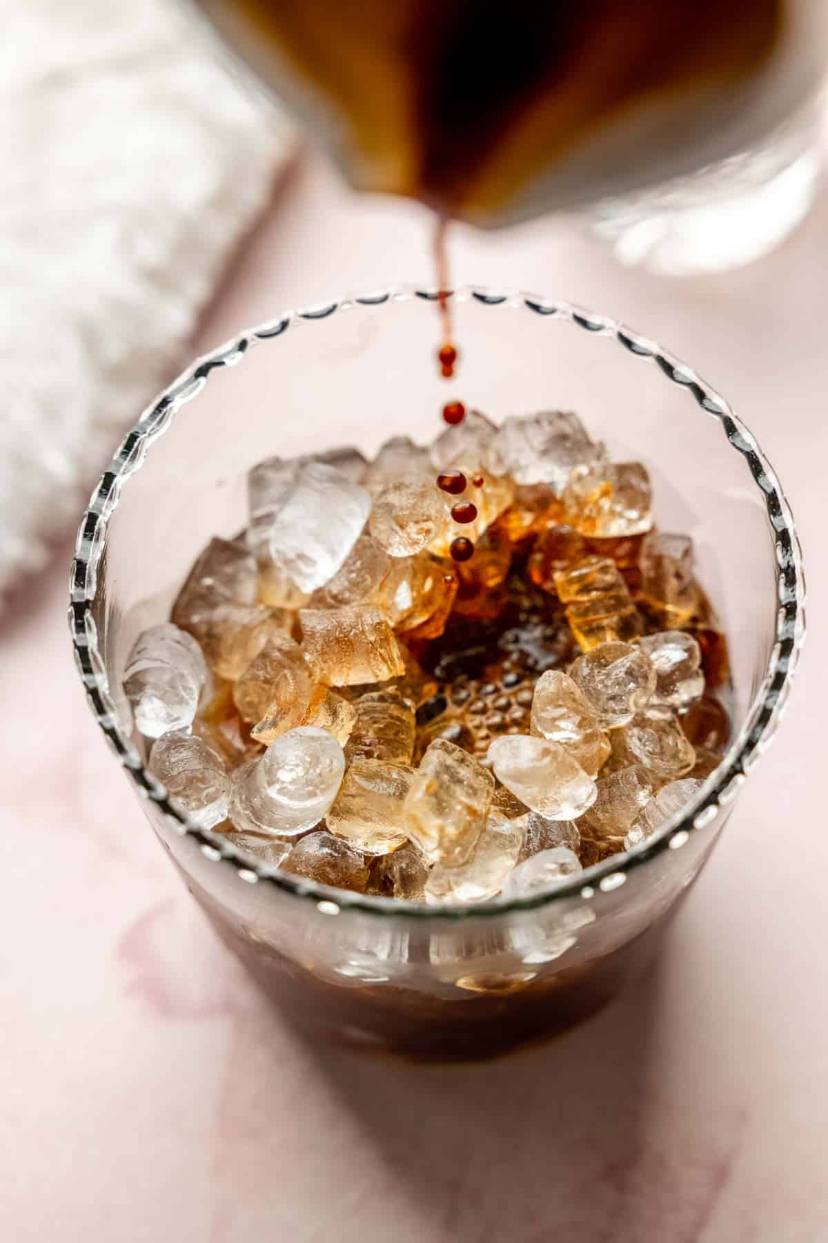 Espresso being poured into the ice-filled glass with lavender syrup.