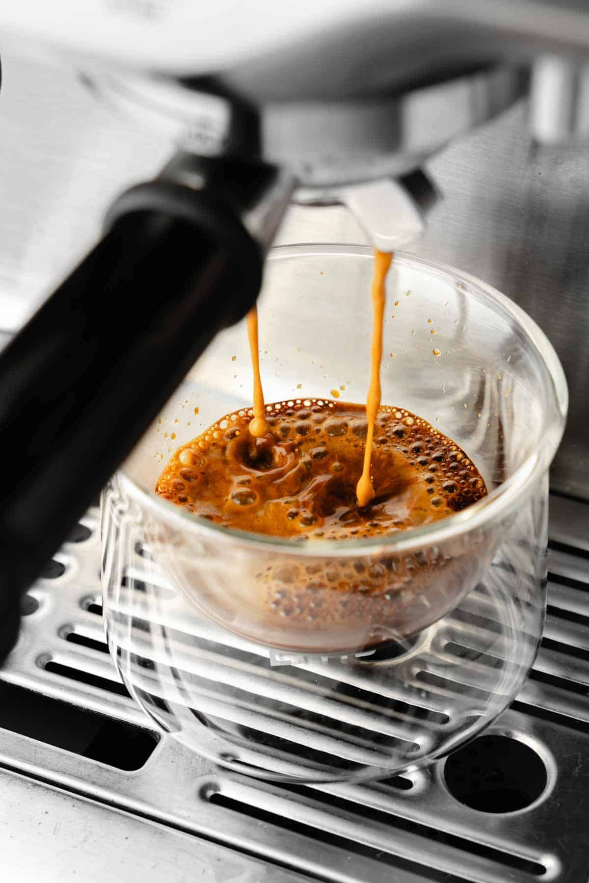 Espresso dripping into glass from espresso machine.