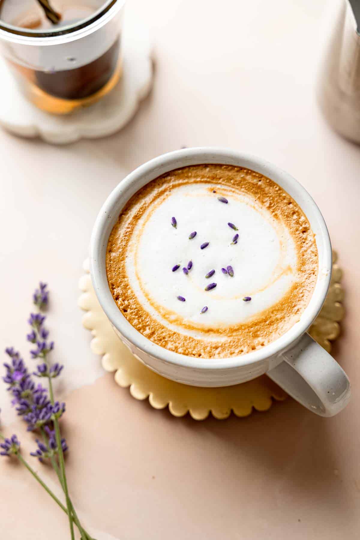 A lavender latte topped with foamy milk and sprinkled with dried lavender buds.
