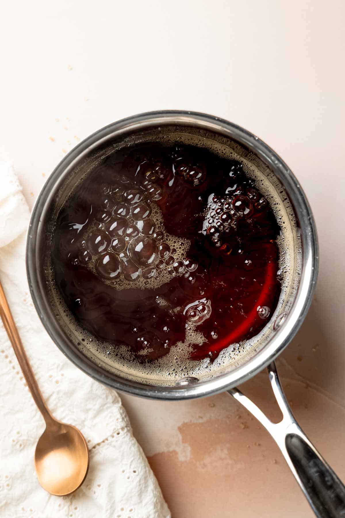Saucepan of bubbling dark liquid cane sugar syrup on the stove.