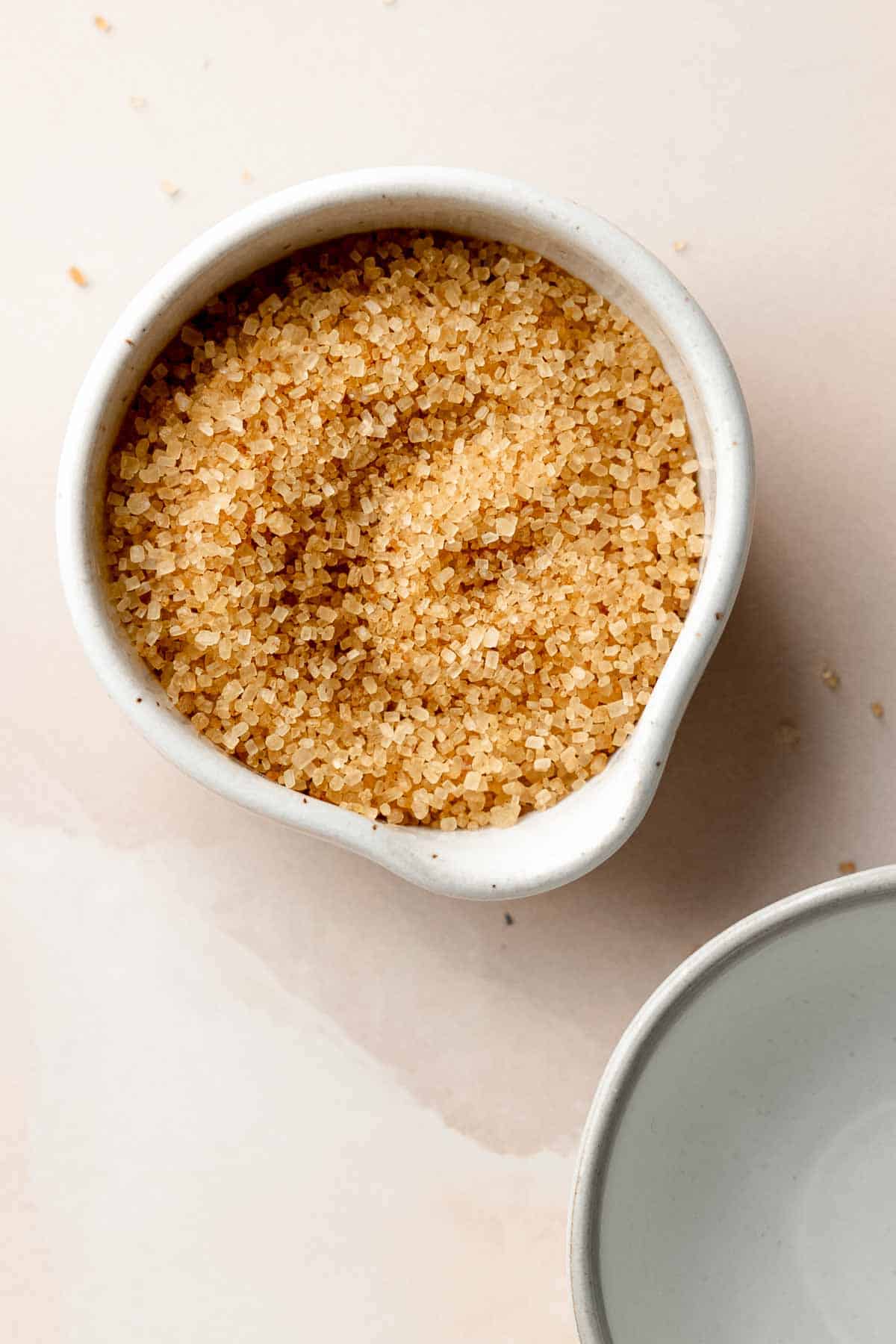 Bowl of raw cane sugar crystals in a small white dish.