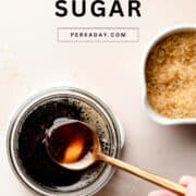 Spoon dipping into a jar of dark liquid cane sugar syrup.